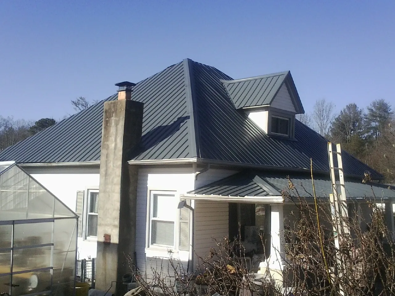 Dark blue standing seam metal roof on a white farmhouse with dormer — Slate & Tile Roof Repair by Roofing Brothers in King Ferry