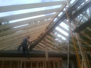 Rafters going up over a new addition with a worker on the wall in King Ferry