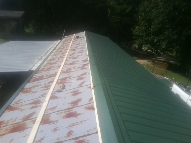 Old rusted panels beside newly installed green metal roofing — Wind Damage Roof Repair by Roofing Brothers in King Ferry