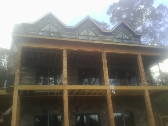 Dormers and porch framing on a large log home under construction — Roof Coating work by our crew in King Ferry
