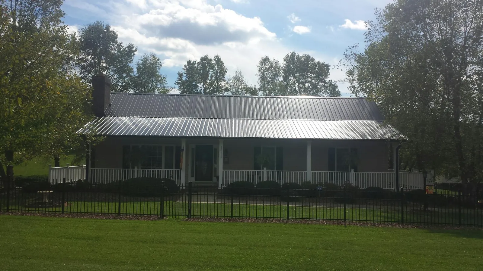 Gray metal roof on a brick ranch with a full width front porch — Gutter Guard Installation work by our crew in King Ferry