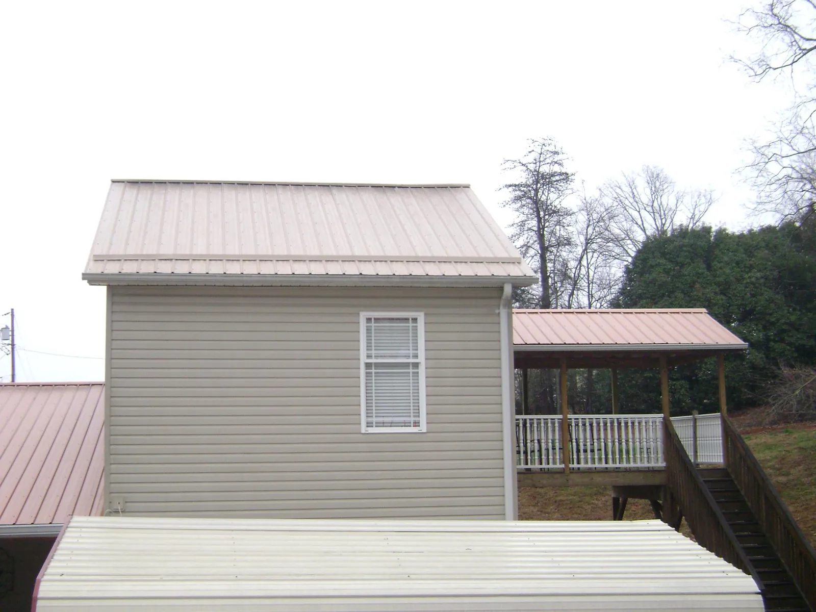 Tan metal roofs on a two story addition and attached porch, from a Roof Replacement job in King Ferry